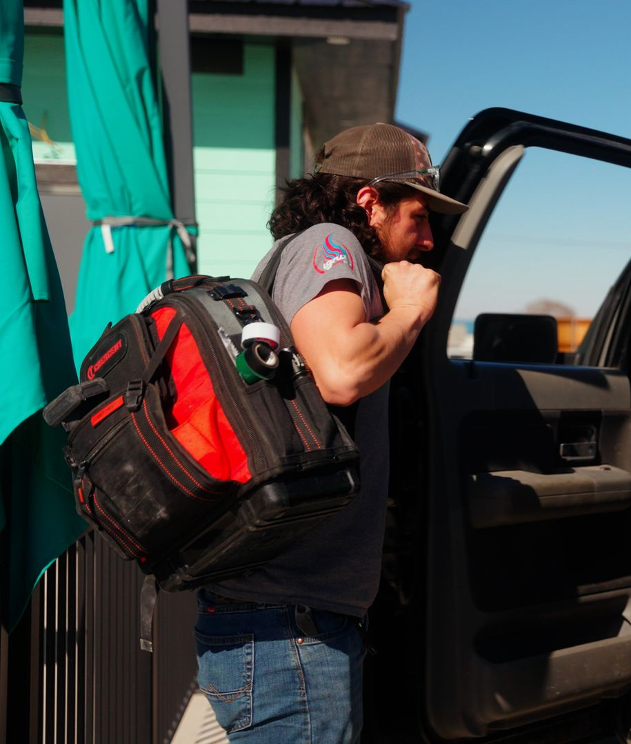 Person with backpack stepping out of an open car door beside a building.