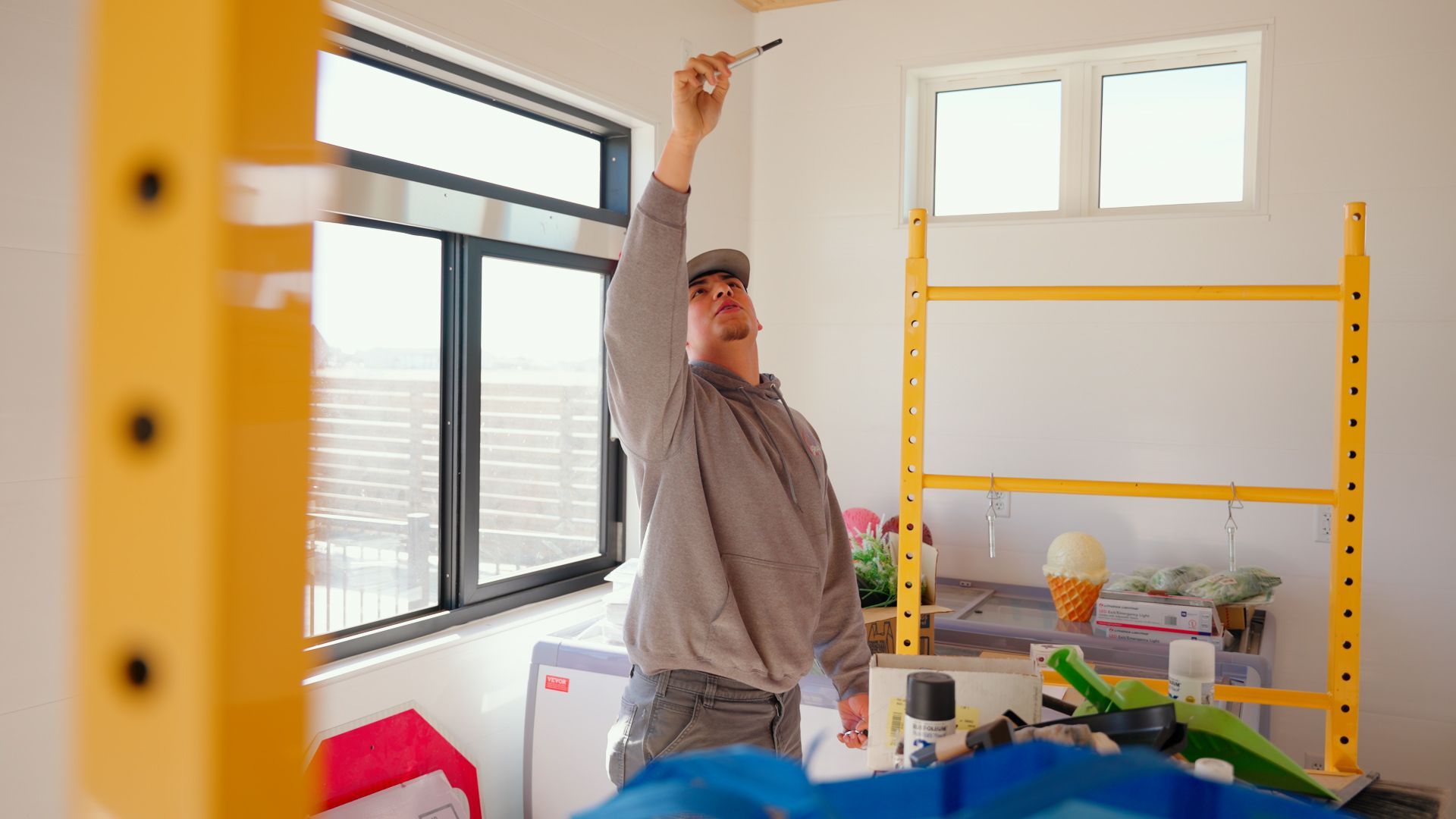 Person stretching in a bright room with a yellow shelving unit and windows.