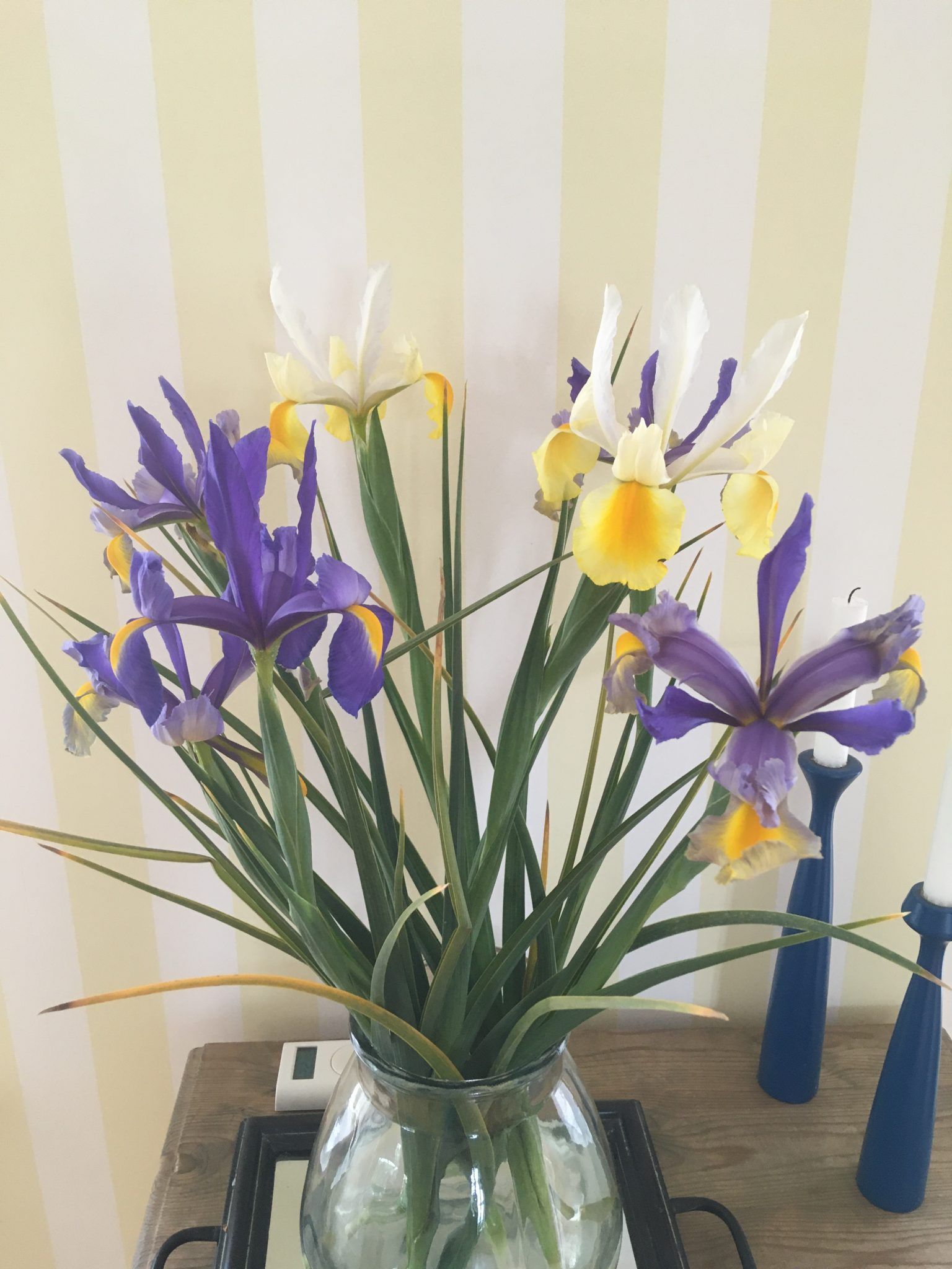 En vase fyldt med lilla og gule blomster står på et bord