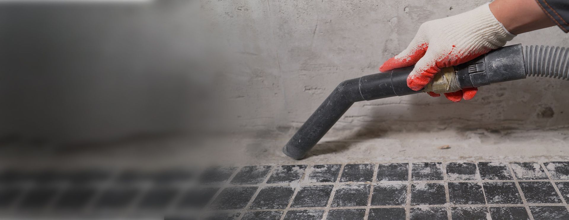 A person is using a vacuum cleaner to clean a tiled floor after construction