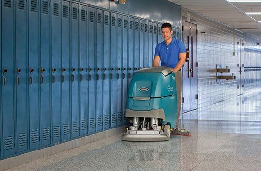 A man is scrubbing floors with a machine
