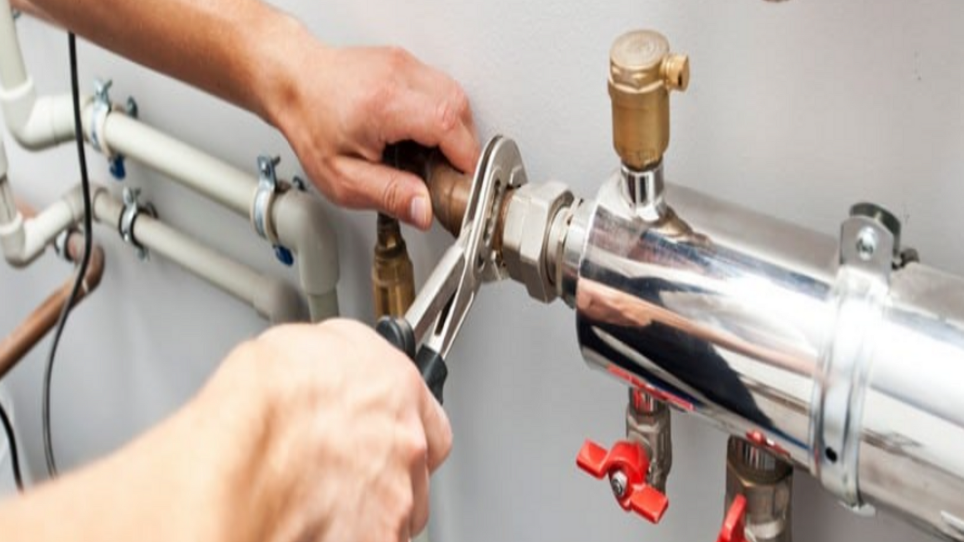 A person is fixing a pipe with a wrench.