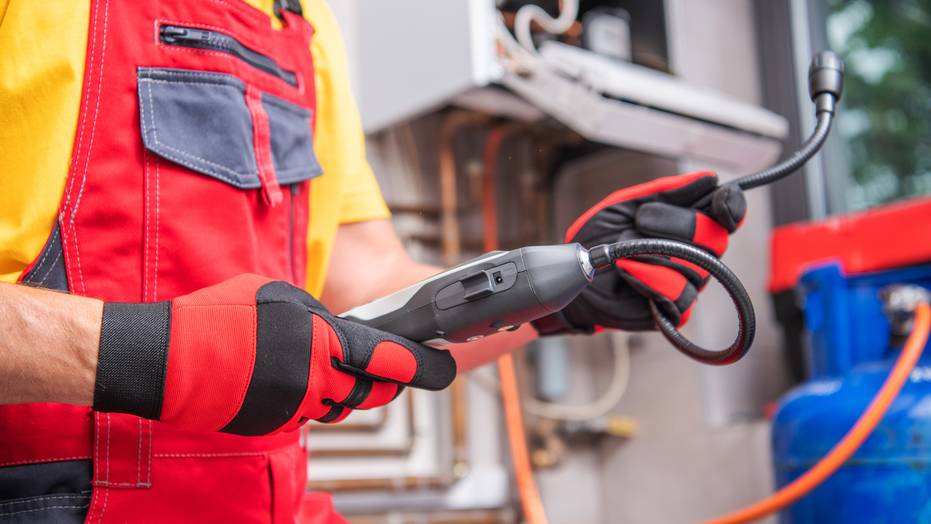 A man in a red and yellow jumpsuit is holding a gas hose.