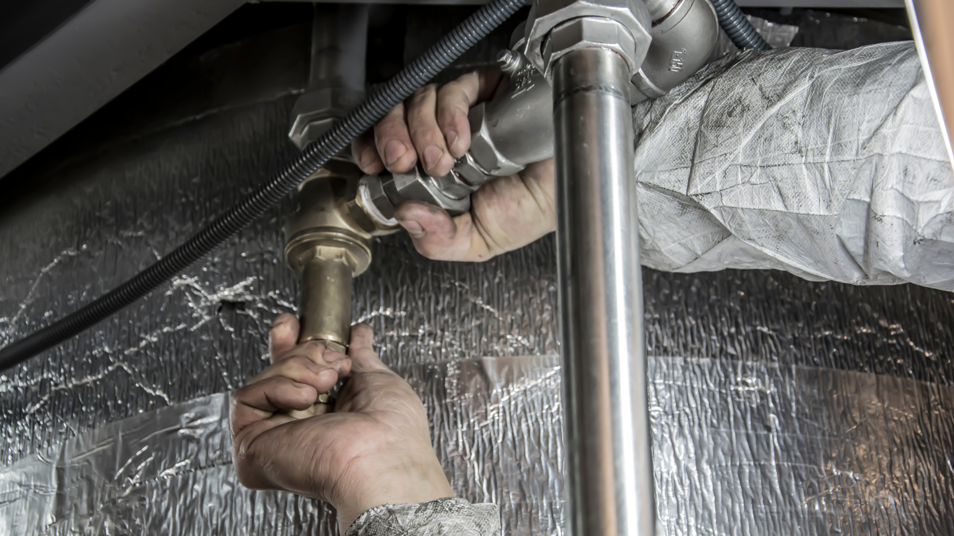 A plumber is fixing a sink pipe with a wrench.