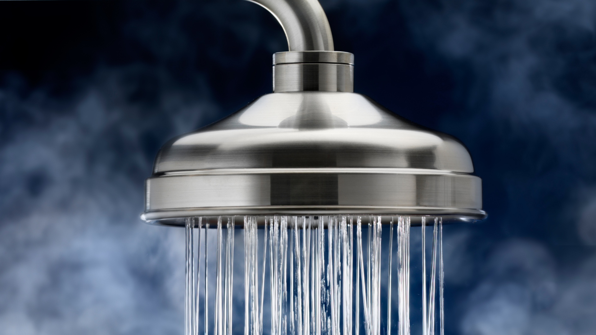 A close up of a shower head with steam coming out of it.