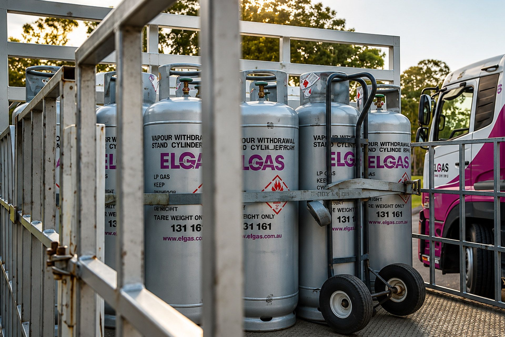 Gas cylinders secured in a metal rack, parked outdoors near a truck.