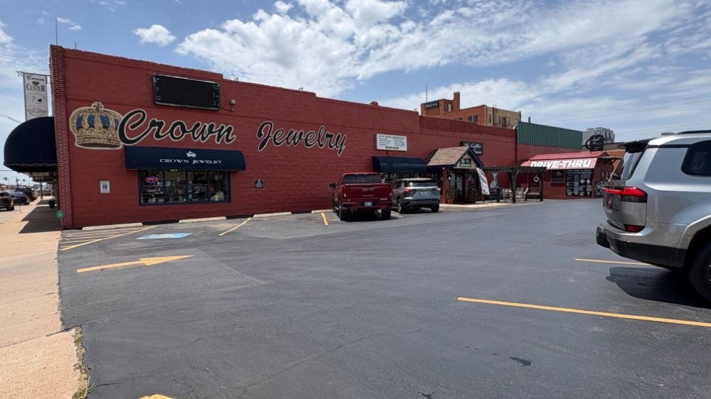 Red storefront with parked cars and outdoor seating under a partly cloudy sky