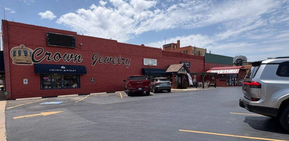 Red brick restaurant storefront with parked cars under a partly cloudy sky