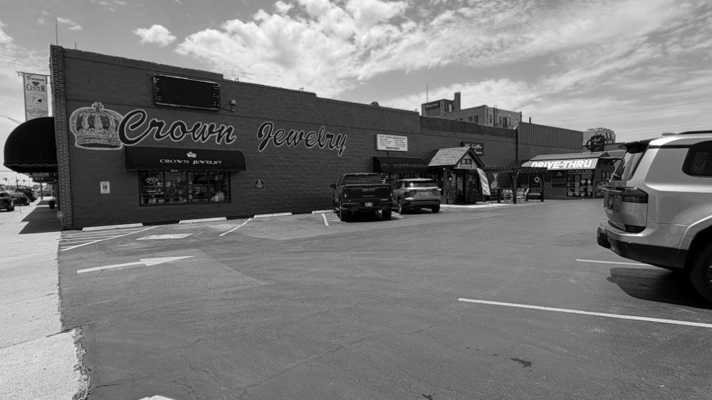 Street view of a storefront with parked cars under a cloudy sky