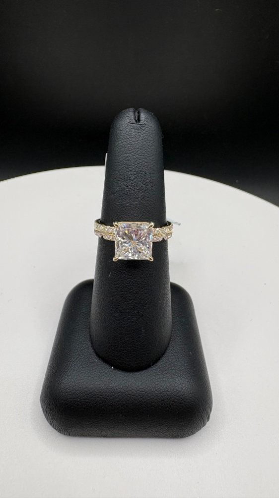Diamond engagement ring on a black display stand against a dark background
