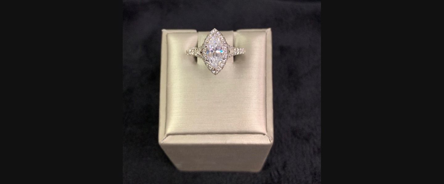 Diamond ring on a cream-colored display box against a black background