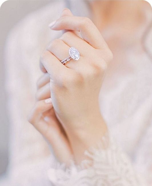 Hands gently clasped, showing a sparkling engagement ring on a lace sleeve
