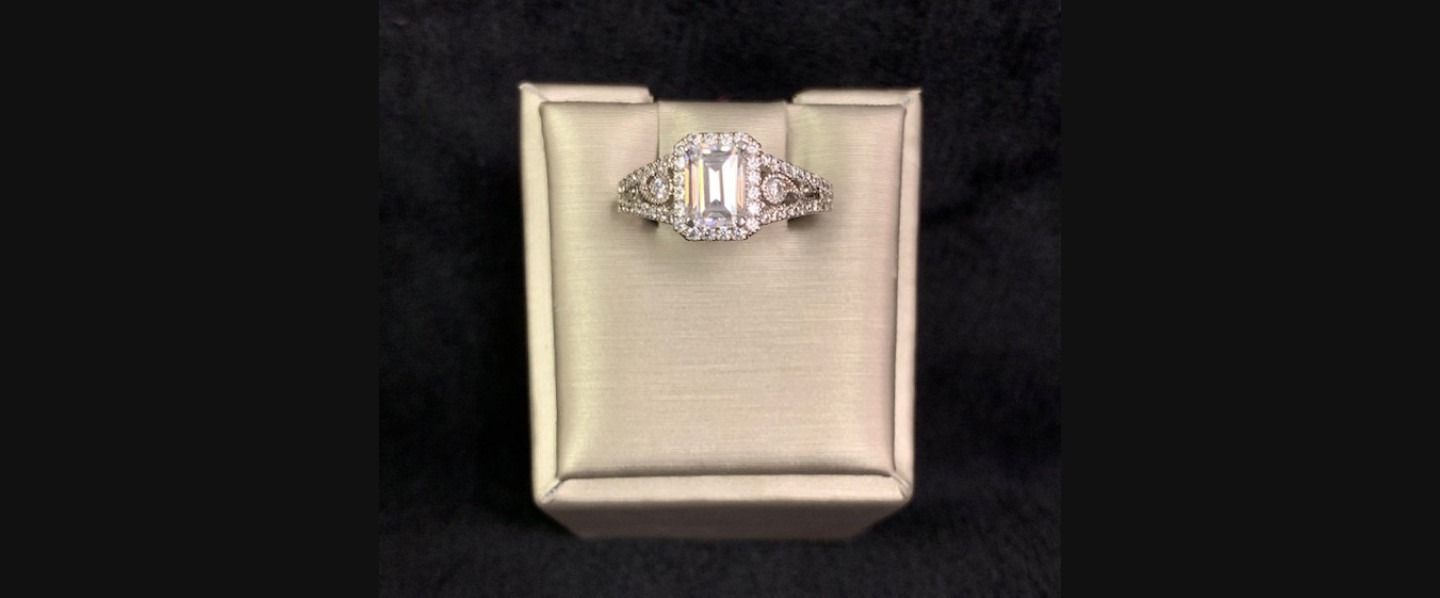 Ring displayed on a beige jewelry box against a black background