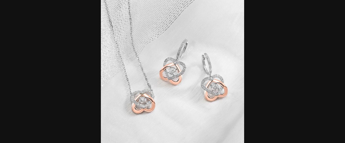 Three rose gold and silver heart-shaped earrings on a white fabric background
