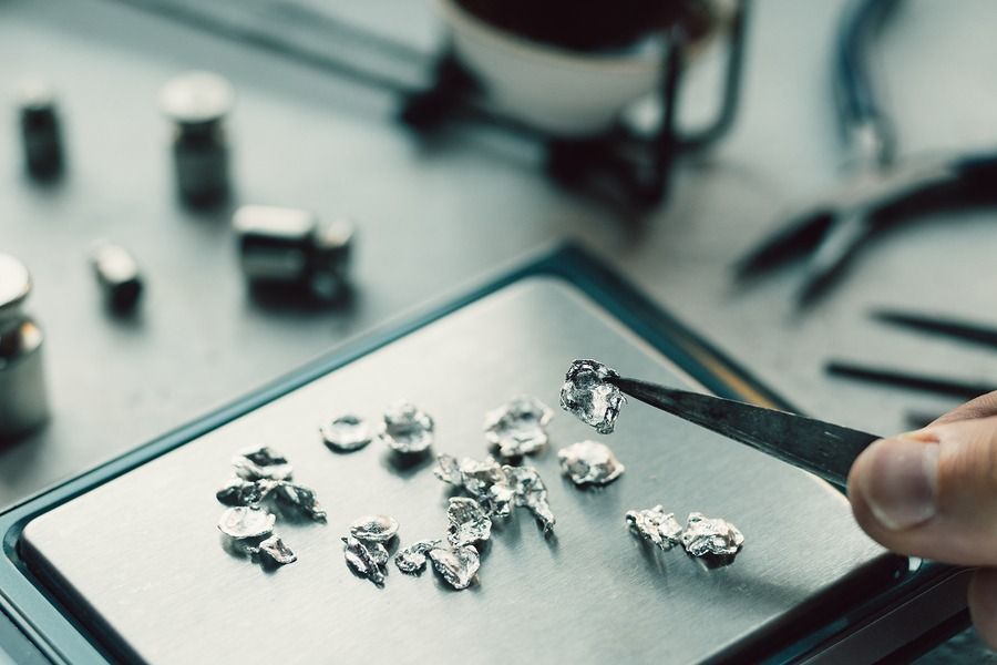Hand placing small silver metal pieces on a tablet in a workshop setting