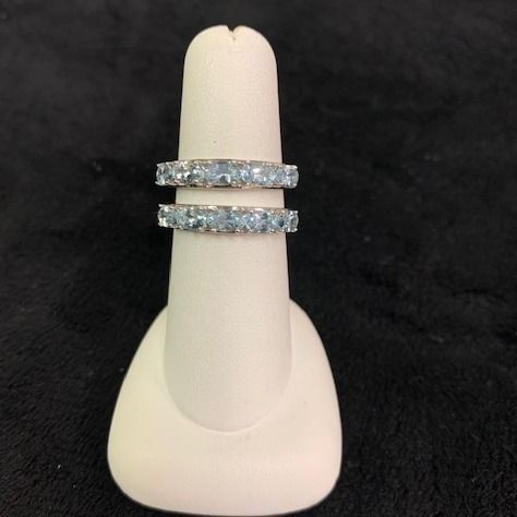 Two silver diamond rings stacked on a beige display stand against a black background