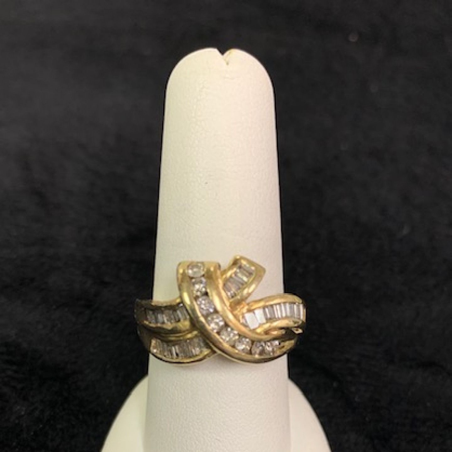 Three gold rings with diamonds displayed on a white finger-shaped stand against a dark background