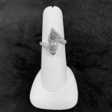 White ring holder with a silver ring displayed on a dark background