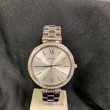 Silver wristwatch with a metal band on a dark fabric background