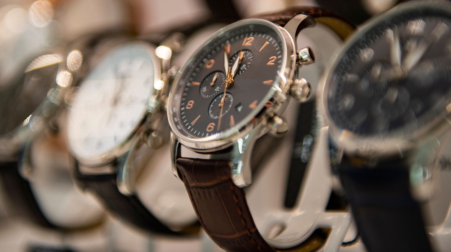 Row of wristwatches on display, with a black-faced watch and brown leather strap in the center