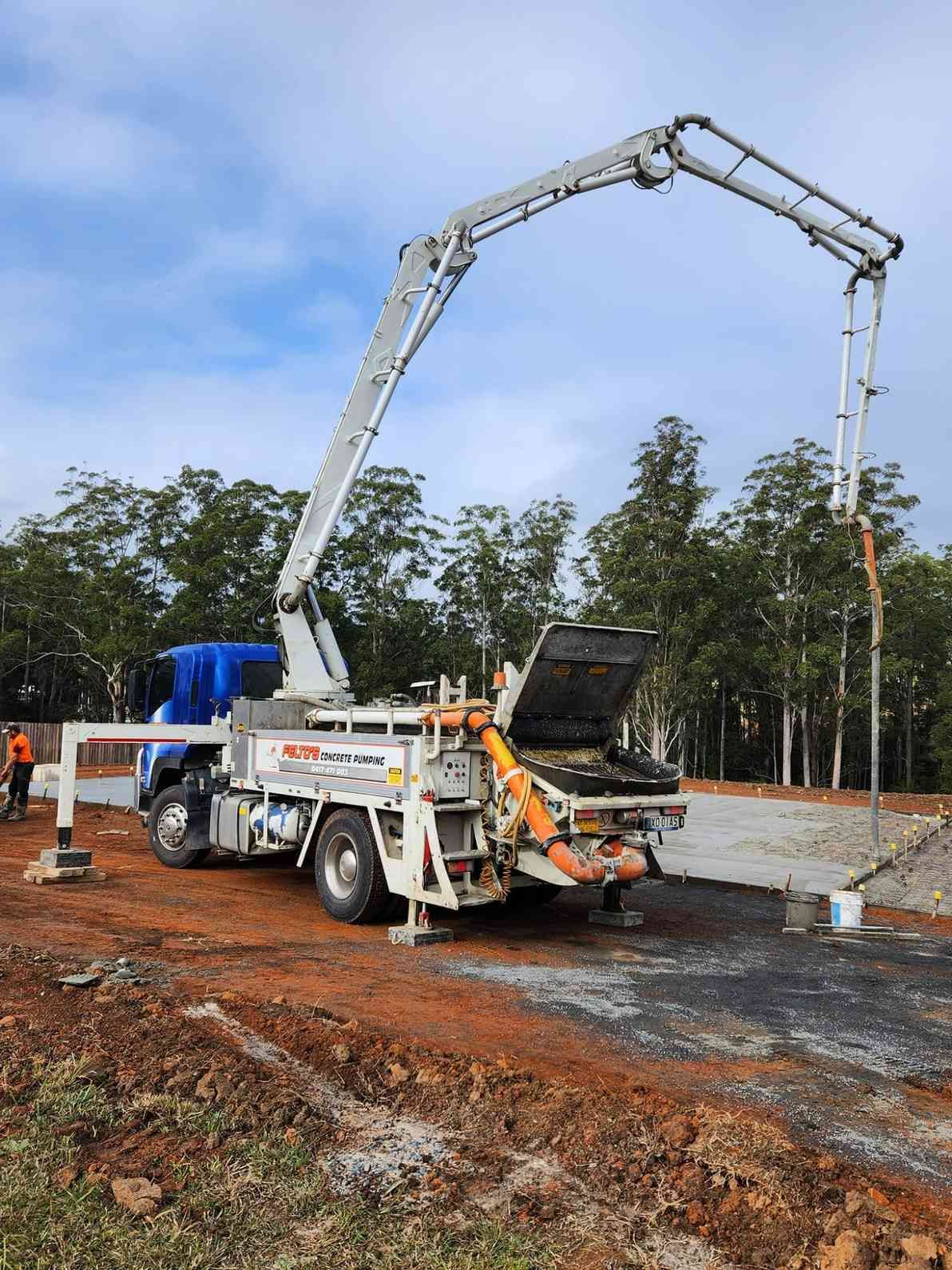 Crew pouring and leveling concrete in large outdoor construction area with pumping truck in background. — Felto's Concrete Line Pumping in Coffs Harbour, NSW