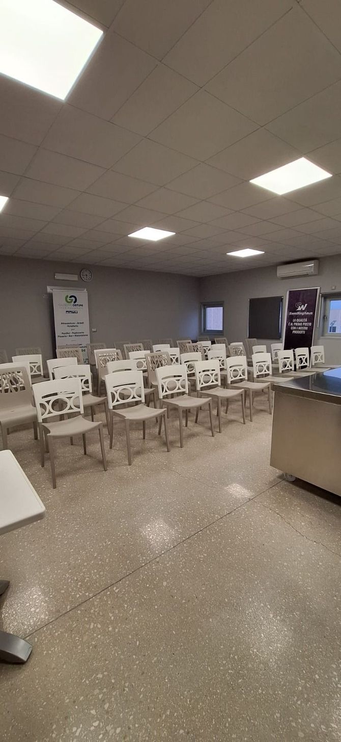 Sala d'attesa vuota con file di sedie, luci fluorescenti a soffitto e distributori automatici lungo la parete di fondo.