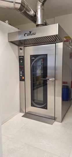 Forni professionali in acciaio inox con porte in vetro e comandi digitali in una cucina, con sistema di canalizzazione sovrastante.