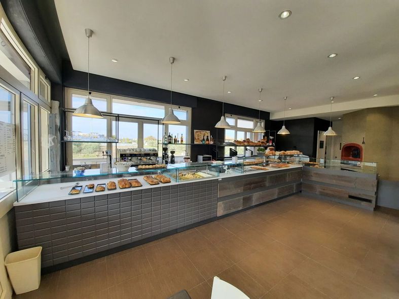 Bancone buffet moderno in una luminosa sala da pranzo con ampie finestre e lampade a sospensione.