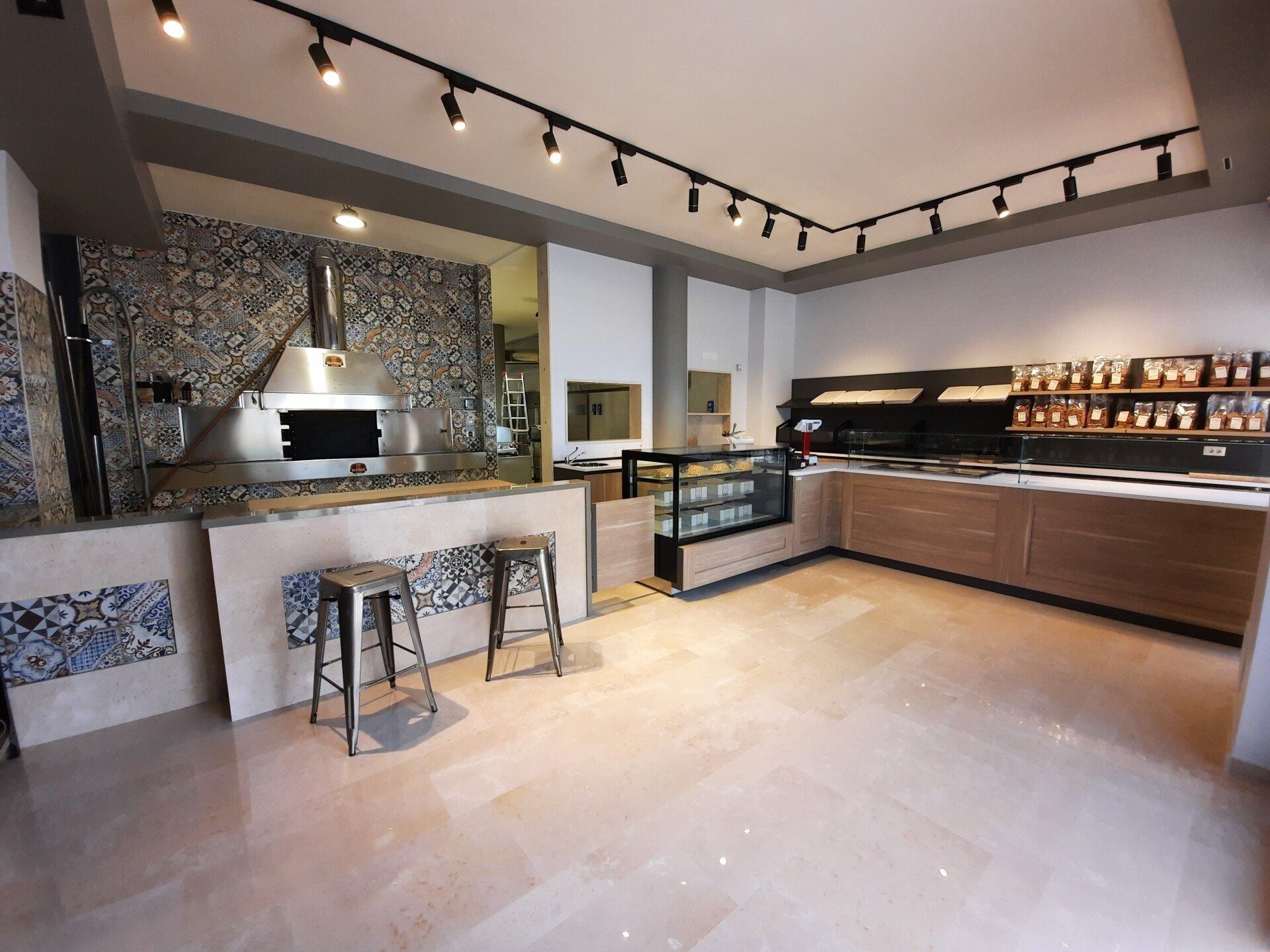 Cucina moderna con isola in pietra, sgabelli da bar e mobili in legno con faretti a binario.