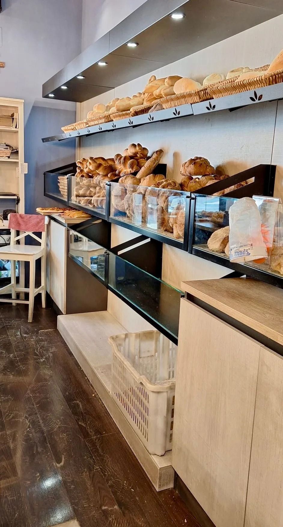 Scaffali da panetteria con un assortimento di pane e pasticcini in un luminoso interno del negozio.