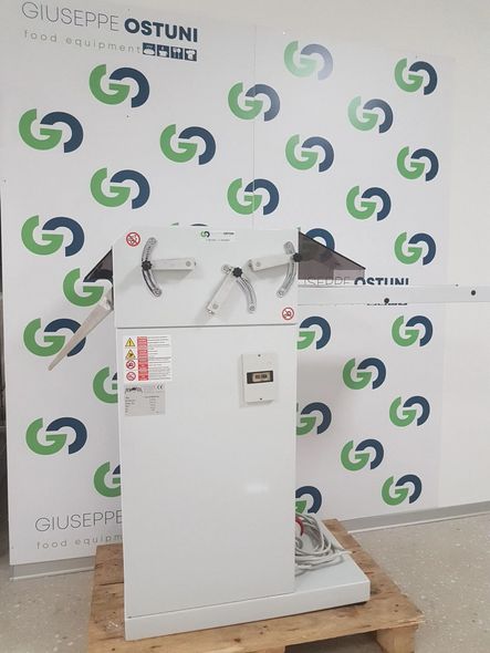 Macchinario industriale bianco su un pallet di legno, appoggiato a una parete con il marchio Ostuni Energy.