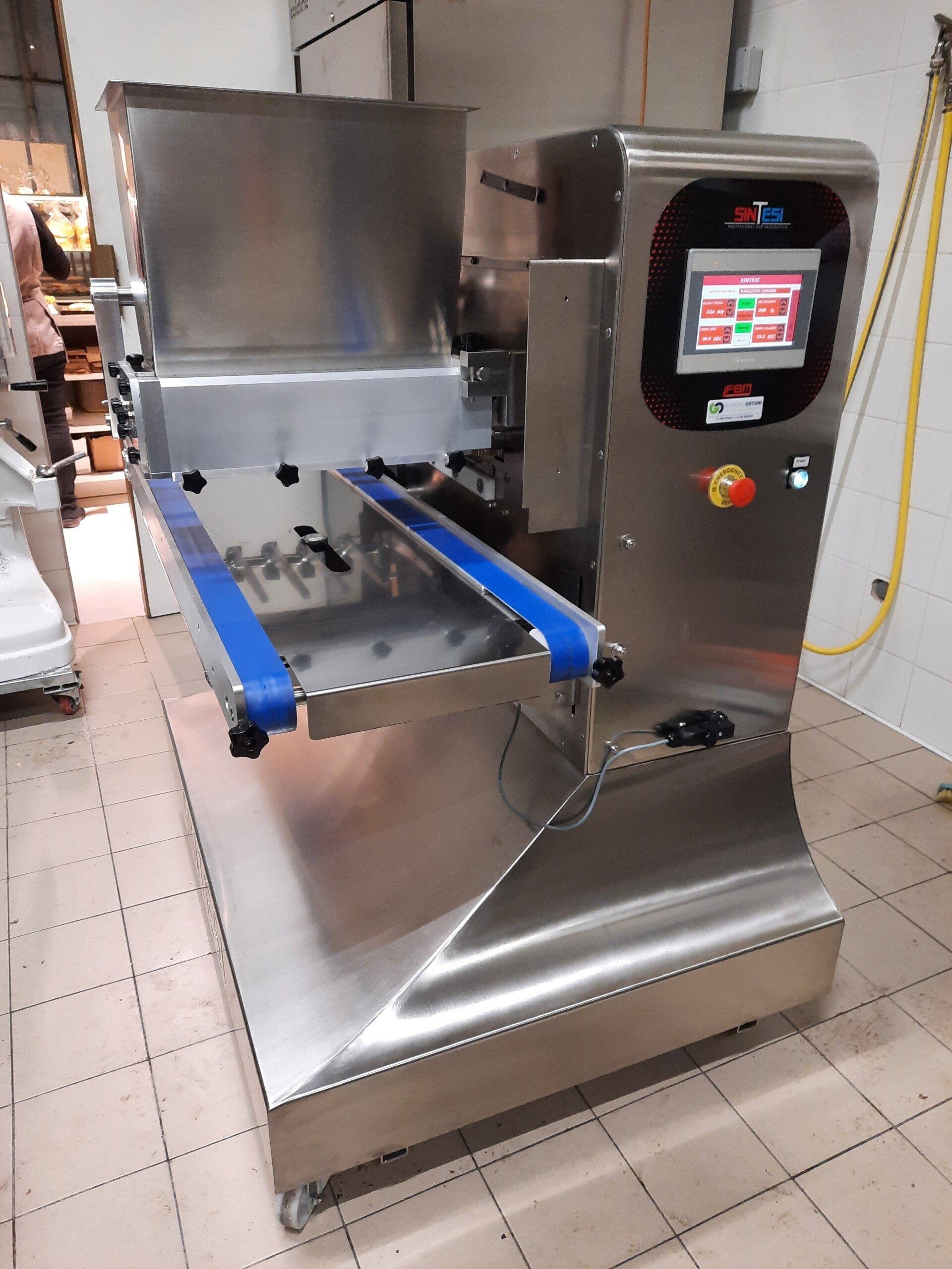 Macchina industriale in acciaio inox con touchscreen e bracci trasportatori blu in un'officina piastrellata.