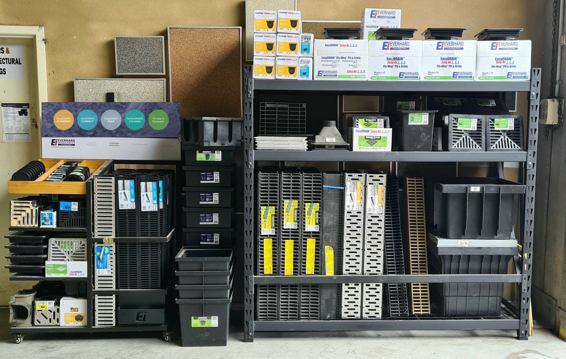 A storage area featuring a metal shelving unit filled with boxes, plastic bins, and industrial hardware components.