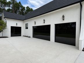 Modern white house exterior with black garage doors and a concrete driveway