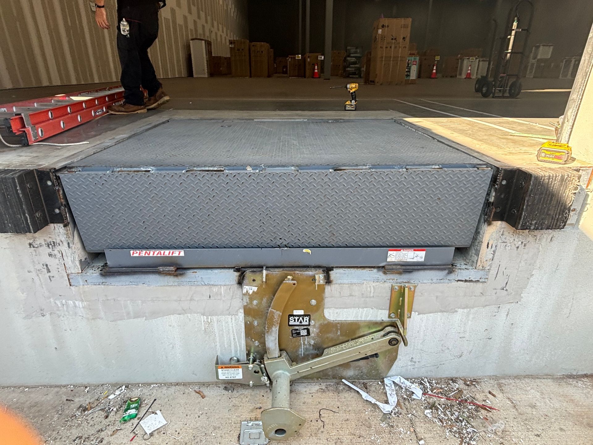 Loading dock with a large dark gray truck liftgate extended over a concrete platform.