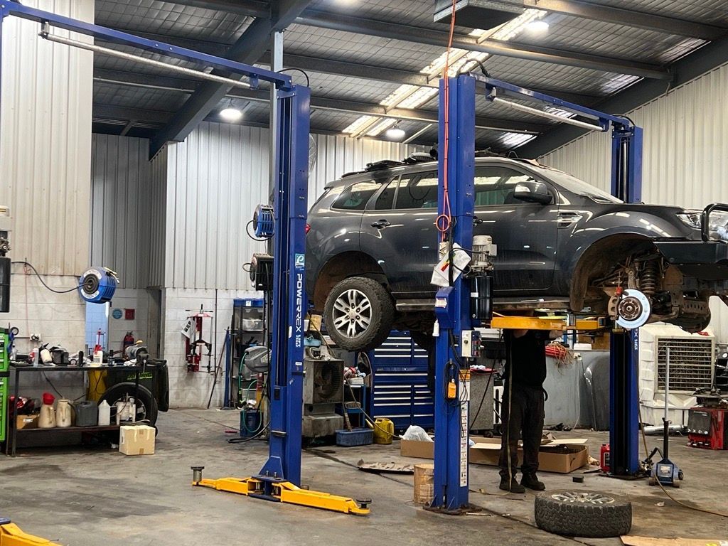 Two Cars at Repair Station One Lifted Above And One On The Ground — Hoist in Parkes