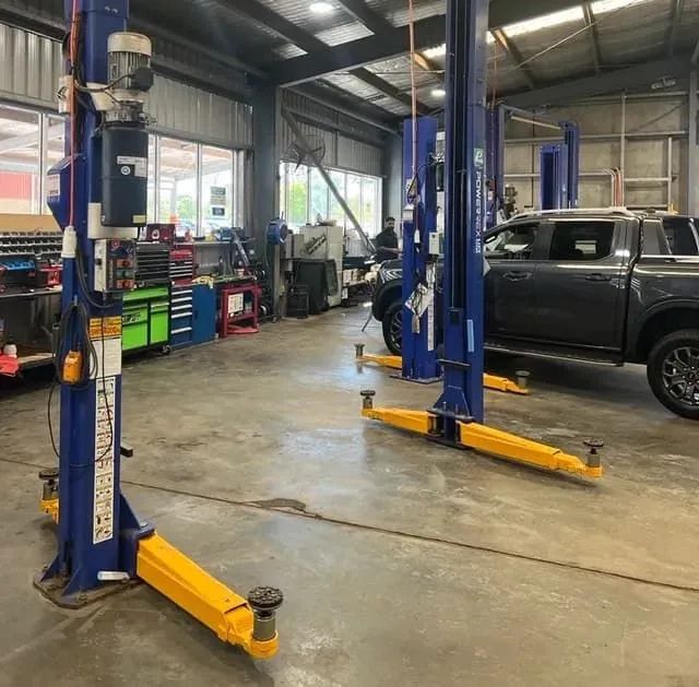 Car Hoist in Mechanic Shop With Black truck Behind It — Hoist in Parkes