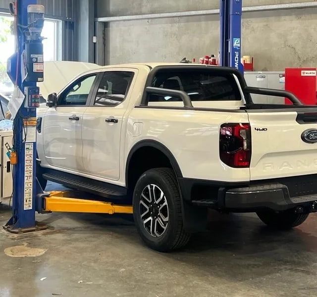 Auto Car Repair Service Center And White Truck Raised By The Hoist — Hoist in Parkes