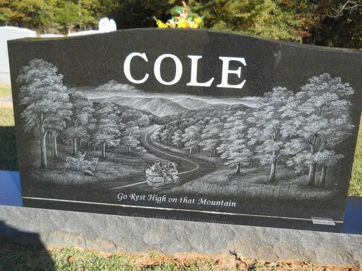 Black granite memorial with “COLE” and a carved mountain landscape scene.