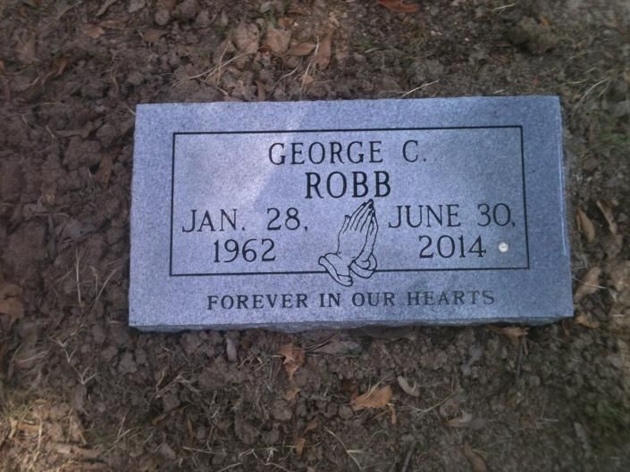 Gray memorial plaque on grass for George C. Robb, Jan. 28, 1962–June 30, 2014, with “Forever in our hearts.”