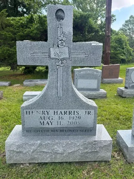 Gray stone gravestone with cross in a cemetery, engraved for Henry Harris Jr., with birth and death dates.