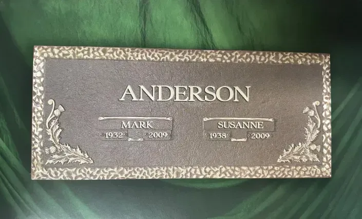 Brown memorial plaque with gold floral border and the name “ANDERSON” centered at the top.