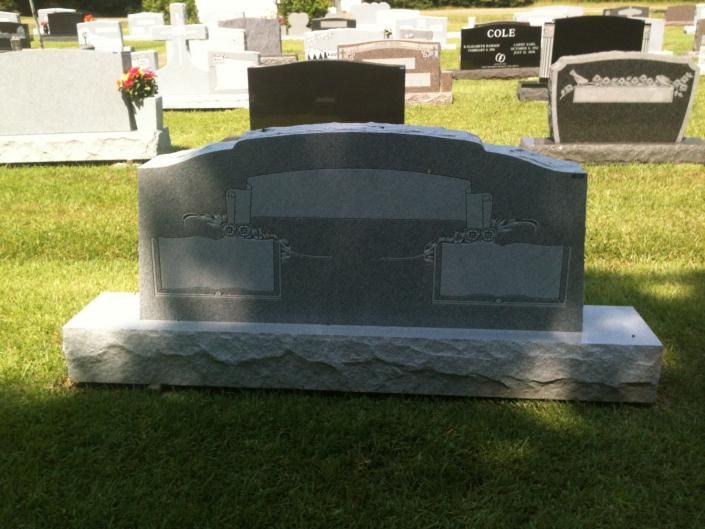 Black granite gravestone on a white base in a sunlit cemetery lawn