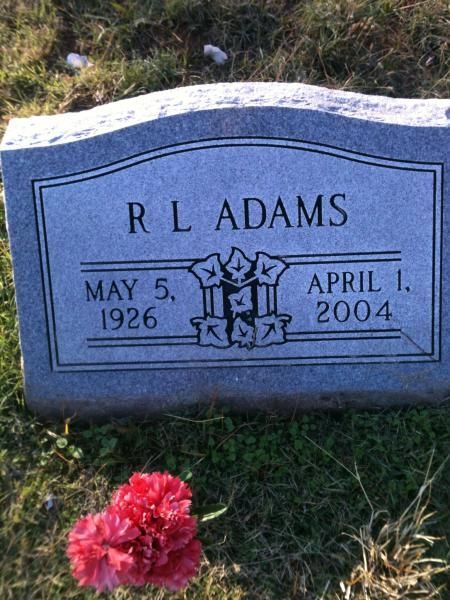 Blue gravestone for R. L. Adams with dates May 5, 1926 and April 1, 2004, with red flowers in front.