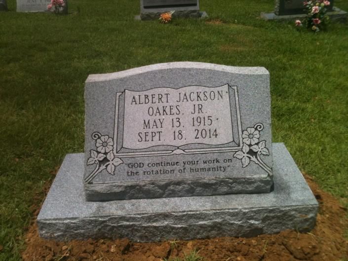 Gravestone on a grassy lawn with flowers, inscribed for Albert Jackson Oakes Jr., May 13, 1915–Sept. 18, 2014