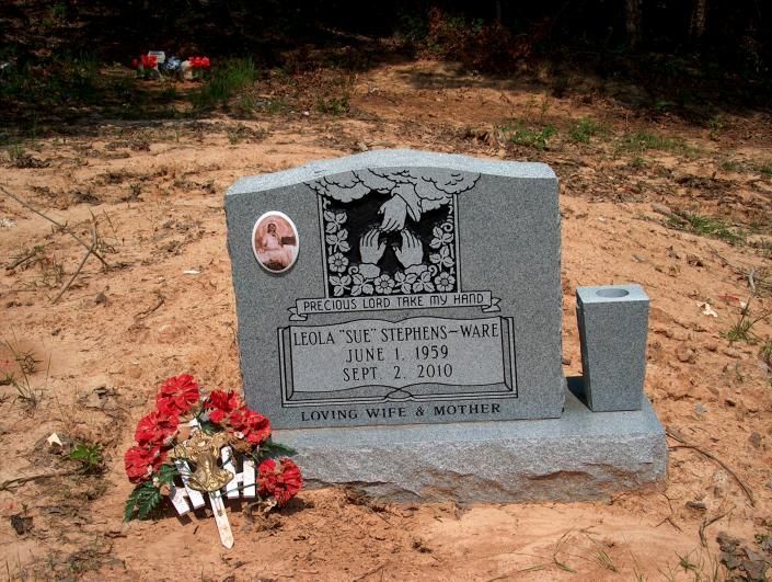 Gray gravestone with flowers at a rural roadside memorial