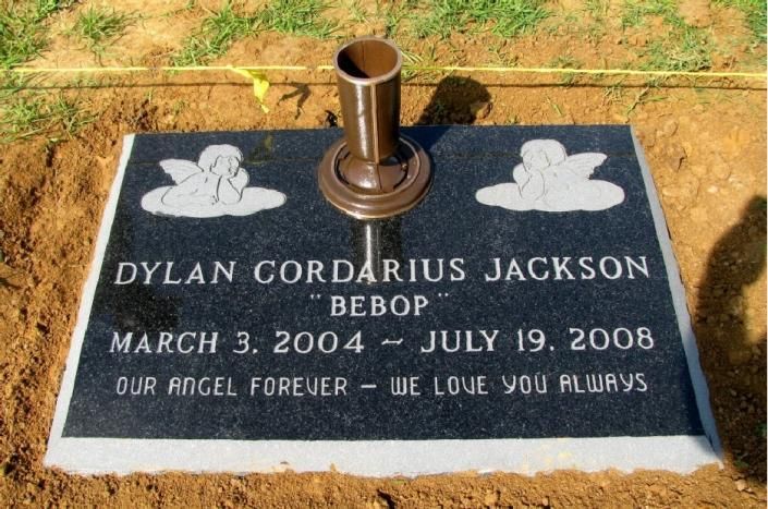 Black grave marker with dog figurines and a vase, inscribed with Dylan Cordarius Jackson, March 3, 2004–July 19, 2008