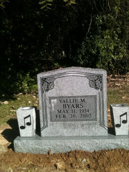 Gravestone with musical note decorations in a cemetery setting