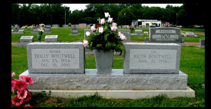 Two gravestones with flower vases in a cemetery, with pink and red flowers on the left.