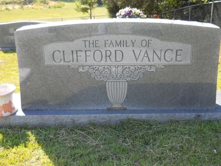 Gray gravestone engraved “The Family of Clifford Vance” in a grassy cemetery.